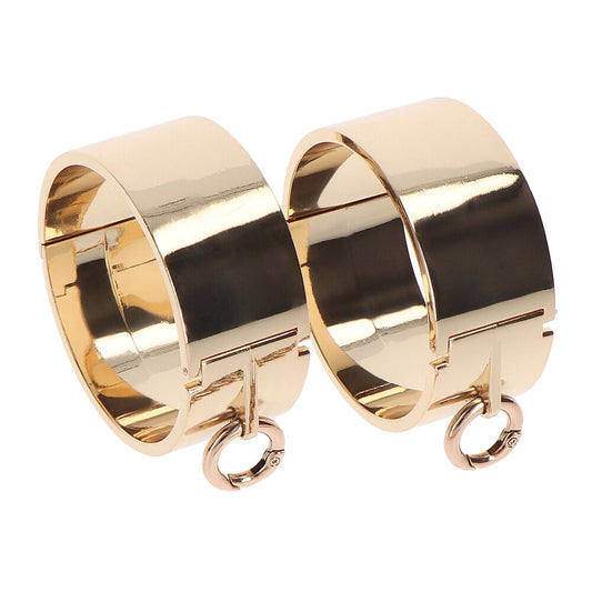Close-up of taboom dona slave wrist cuffs, shiny metal with soft black padding.