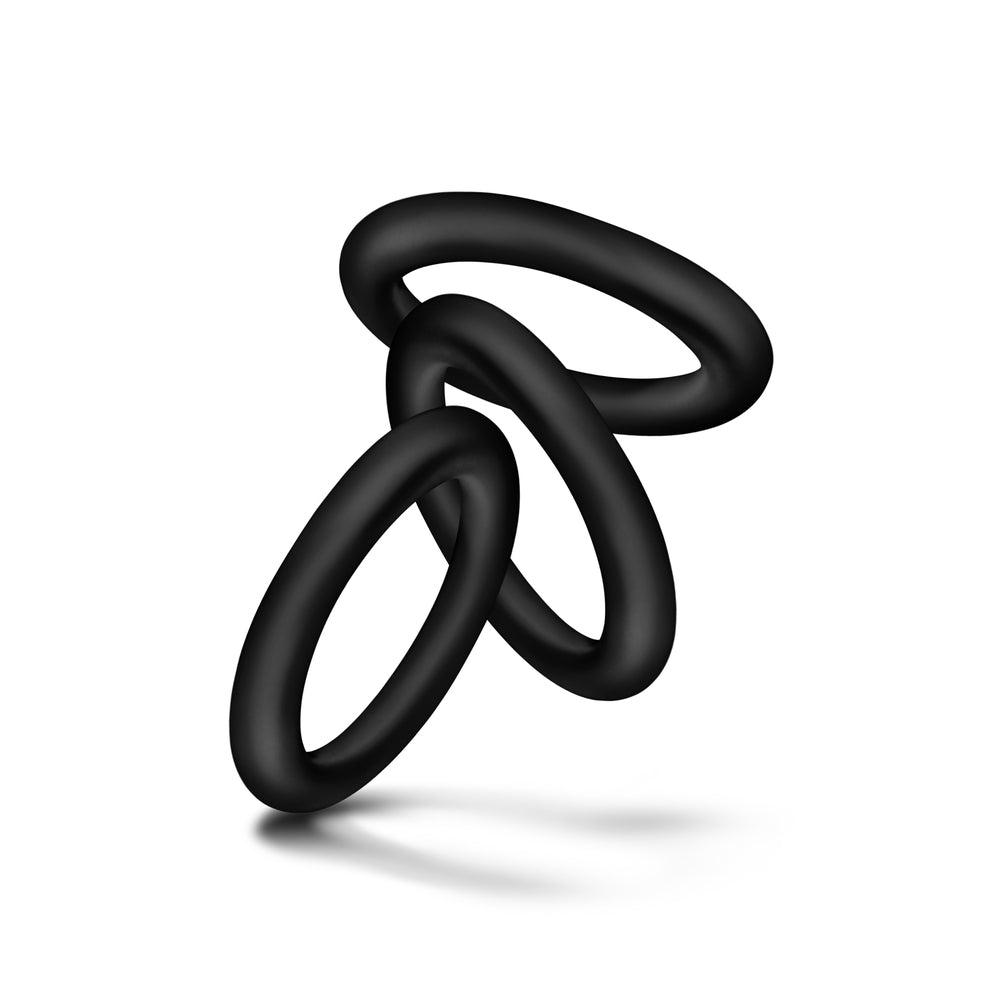Close-up of three small, smooth, dark grey love rings for enhanced male performance.