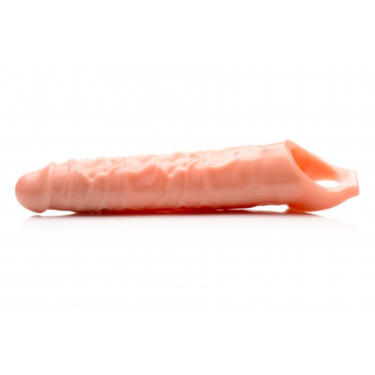 Close-up of a flesh-toned, textured penis extender sleeve, approximately three inches long.