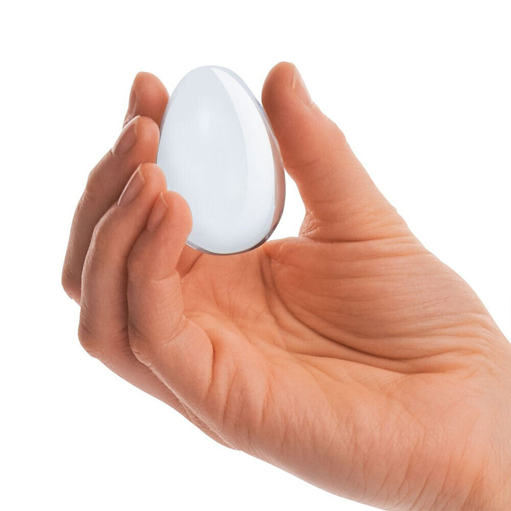 Two clear glass yoni eggs, polished and smooth, from various toy brands, for intimate use.