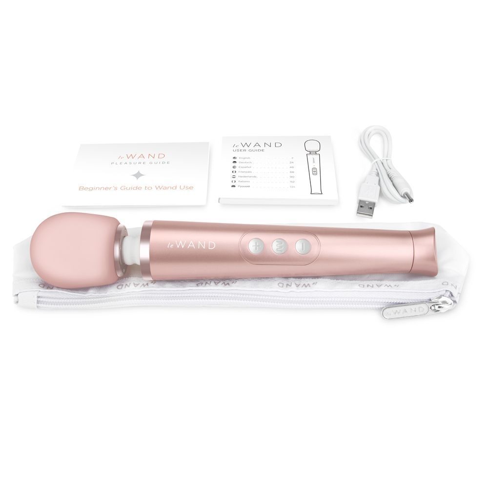 Close-up of a petite gold Le Wand rechargeable wand massager, showing its smooth finish.